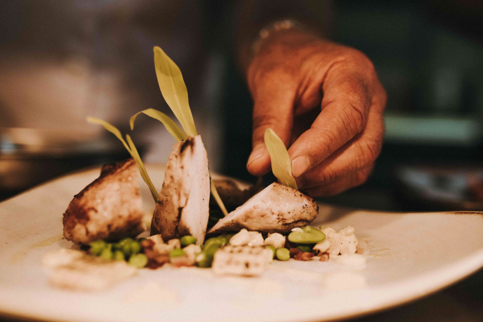A chef plating up a chicken dish.