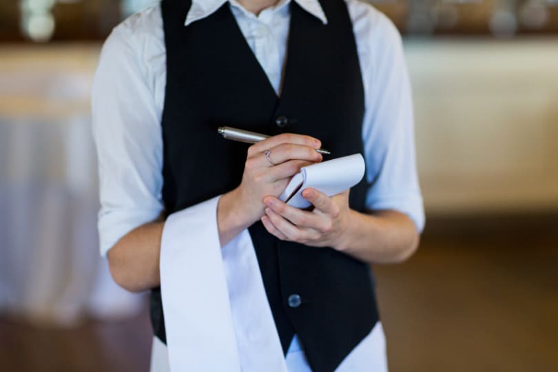 A waiter dressed smartly taking an order