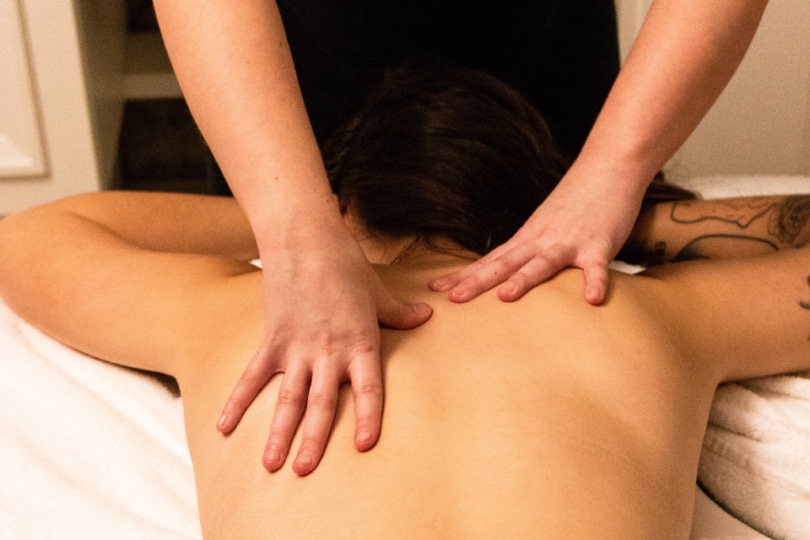 A lady laying face down getting a her shoulders massaged