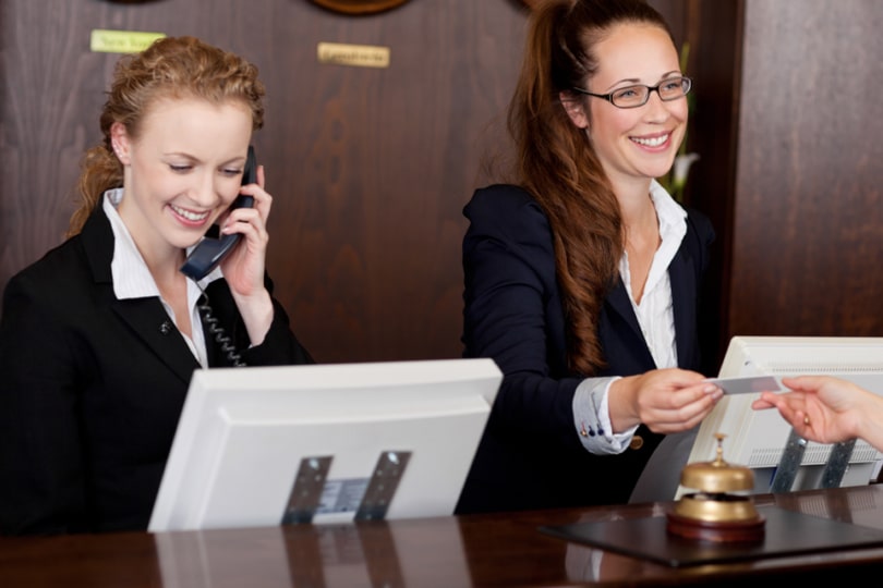 Two female hotel receptionists at work behind a desk
