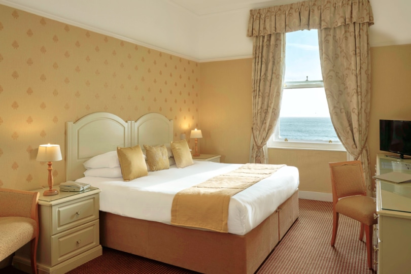 One of the sea view rooms showing it's bed, dresser, table, chair and the view from the window